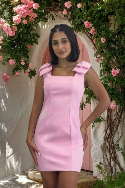 Woman in a pink dress standing in front of floral decorations