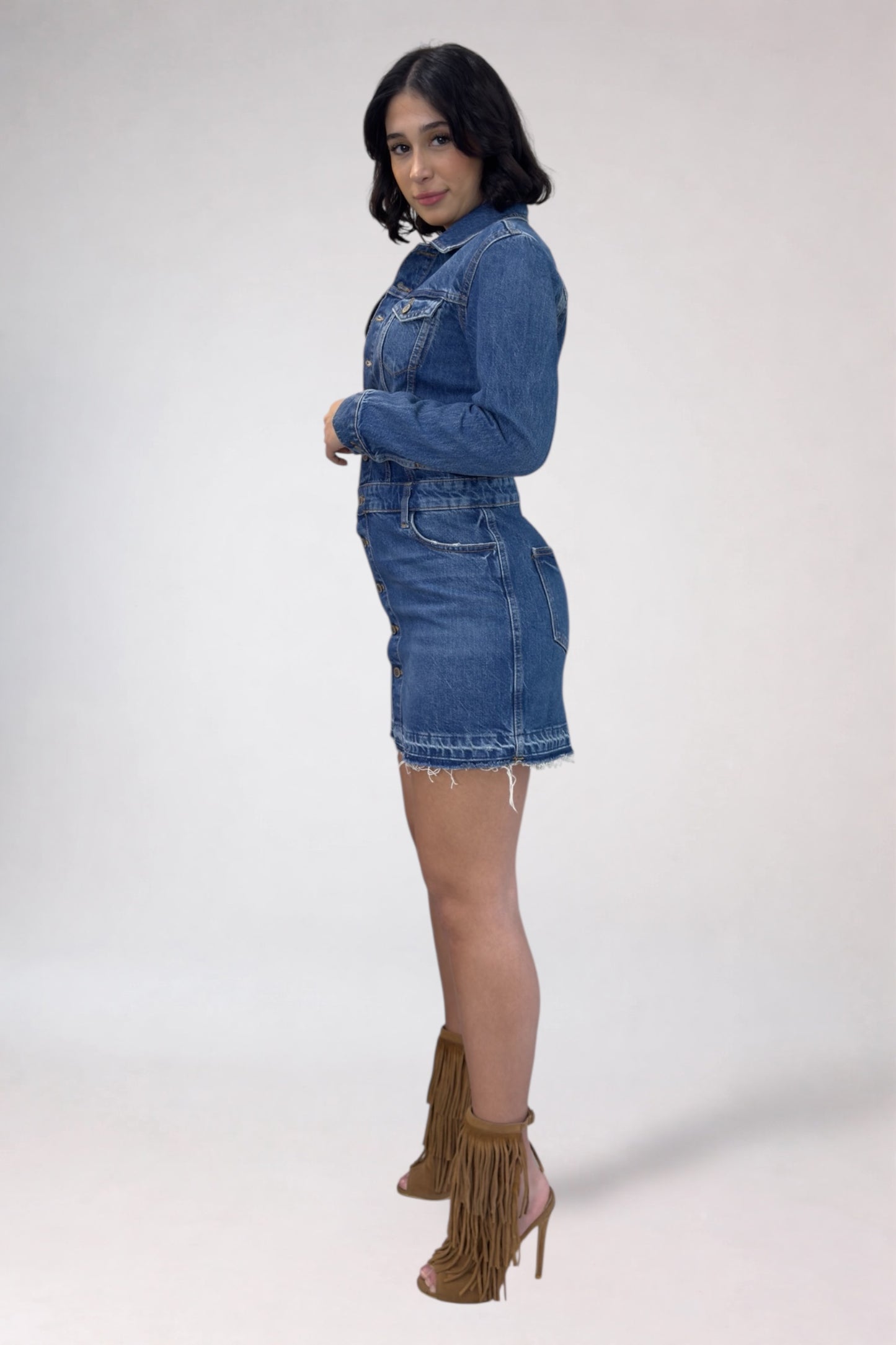 Woman wearing a denim dress with fringed high-heeled boots on a white background