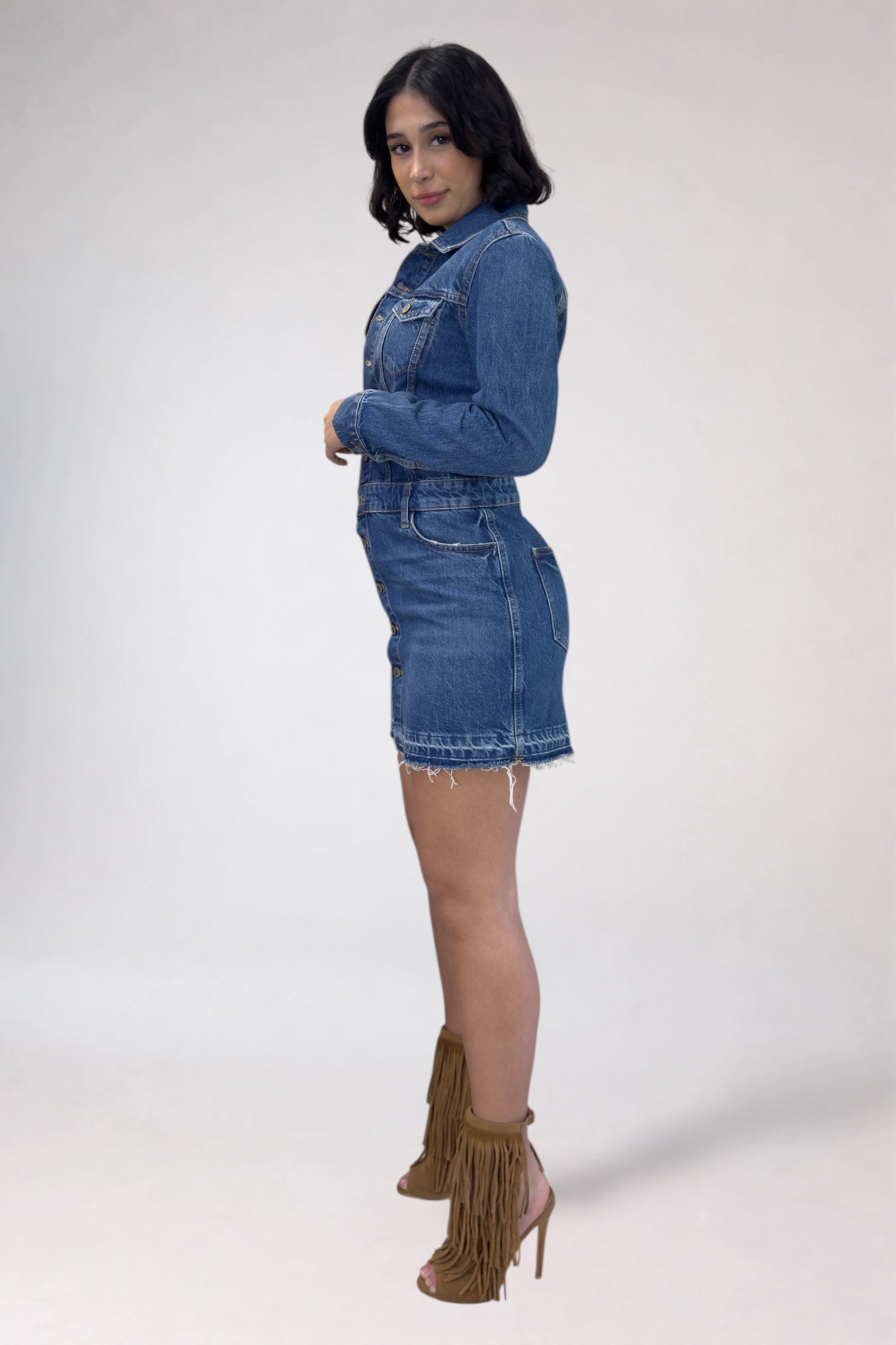 Woman wearing a denim dress with fringed high-heeled boots on a white background