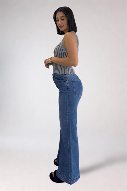 Woman wearing a striped sleeveless top and blue jeans on a white background