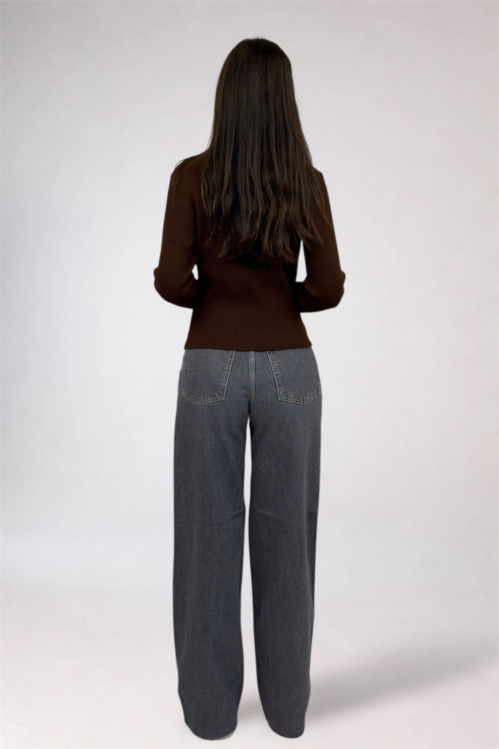 Person wearing a brown top and gray pants on a white background