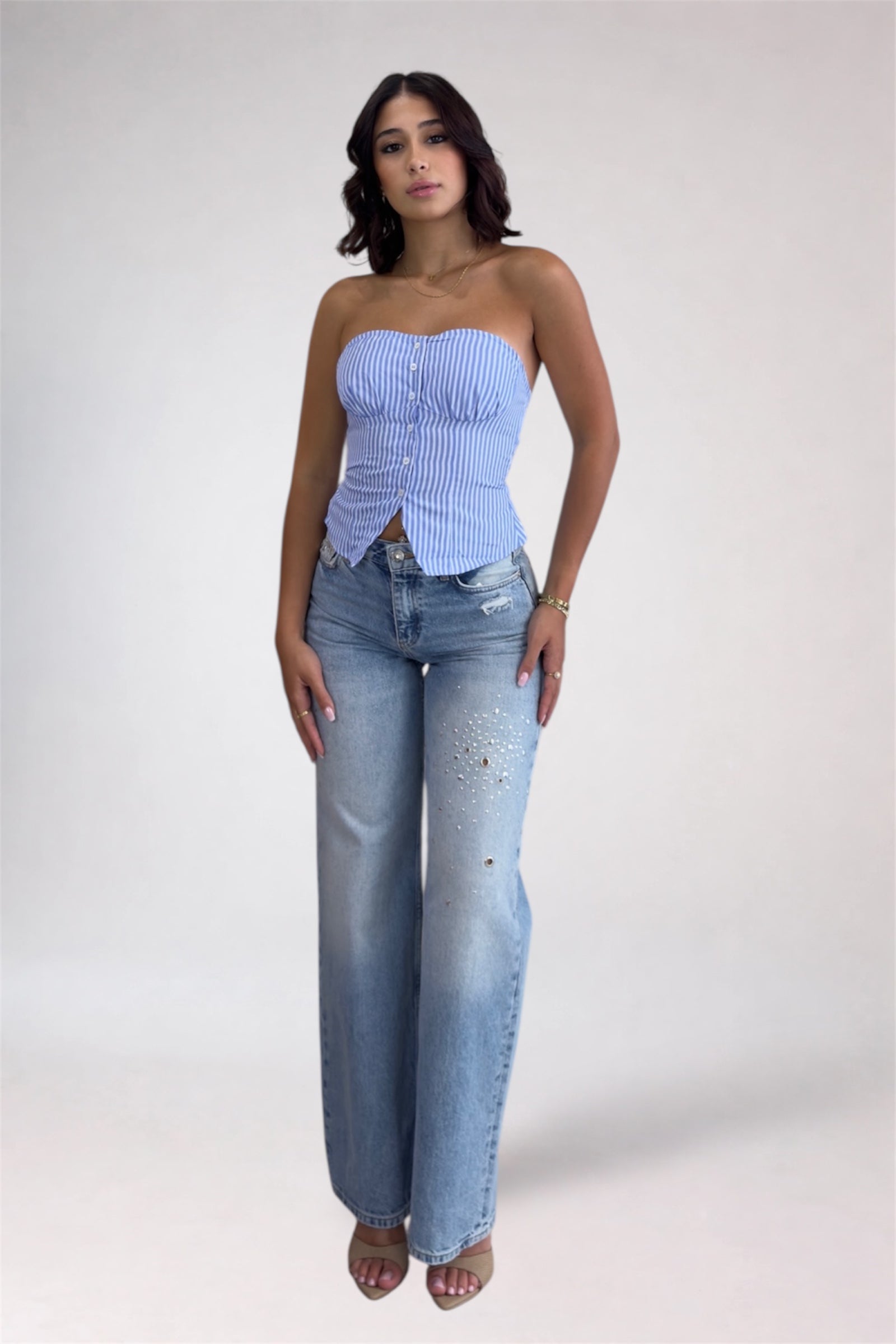 Woman wearing a light blue strapless top and jeans on a white background