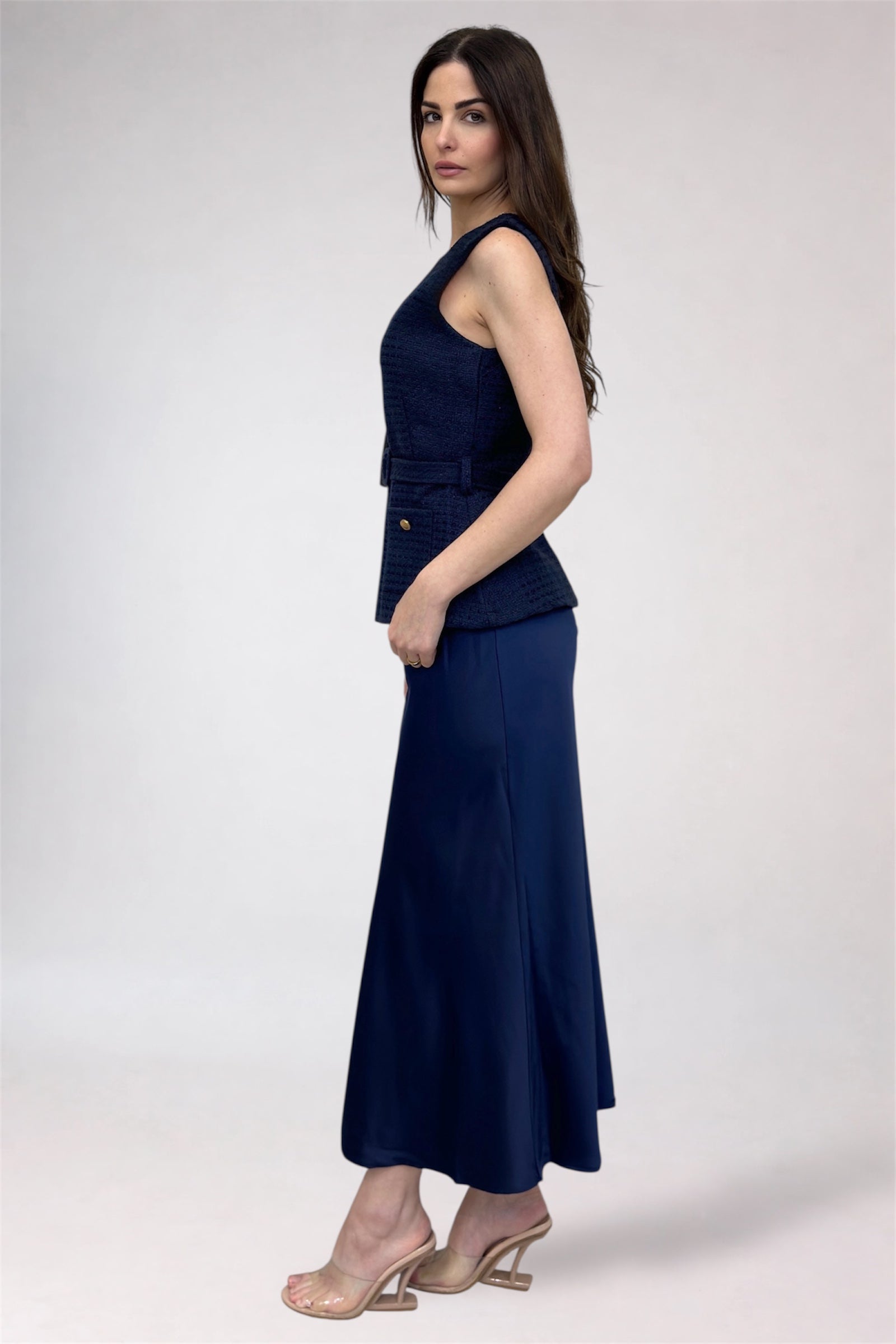 Woman wearing a navy blue sleeveless top and long skirt on a white background
