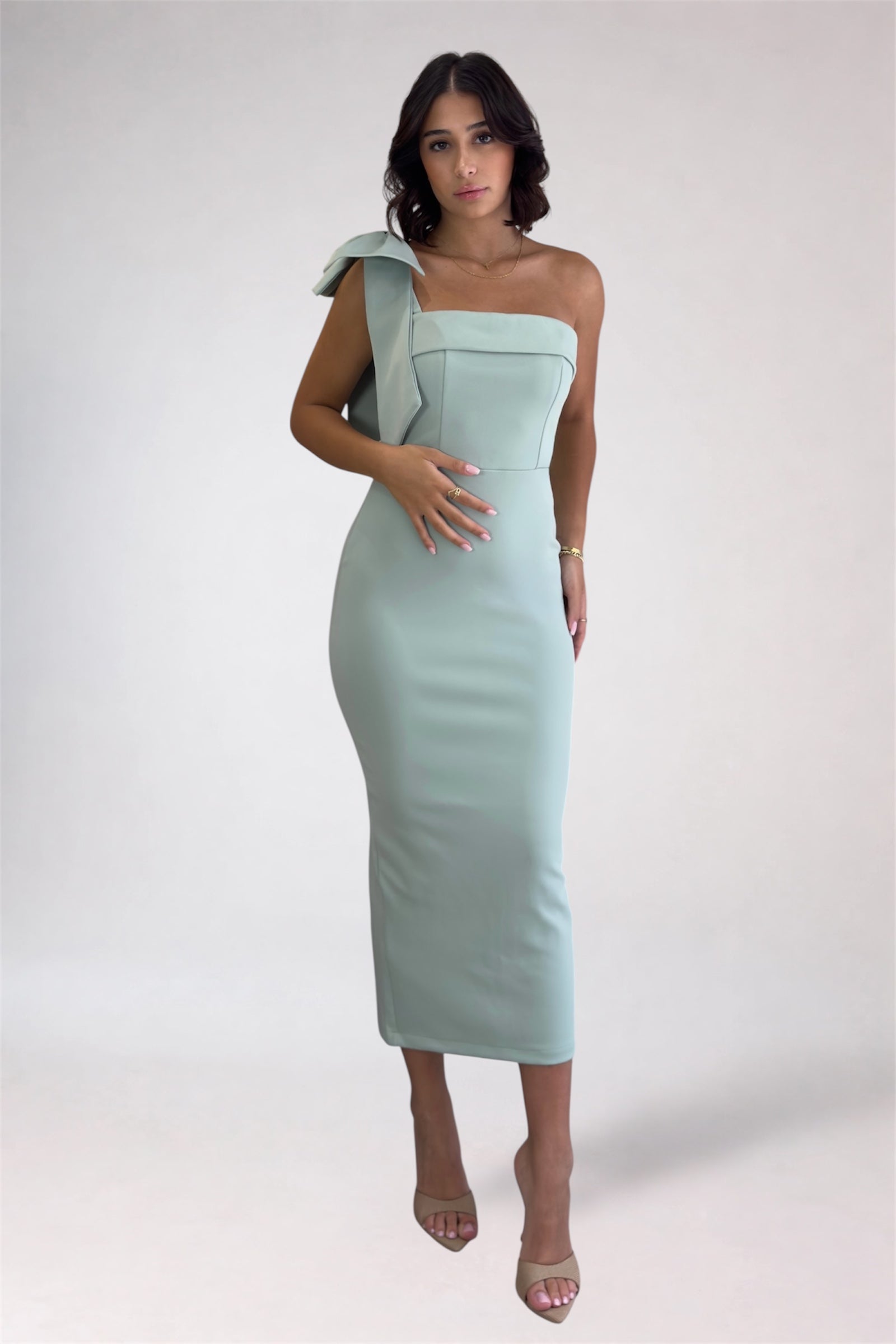 Woman wearing a light blue one-shoulder dress on a white background