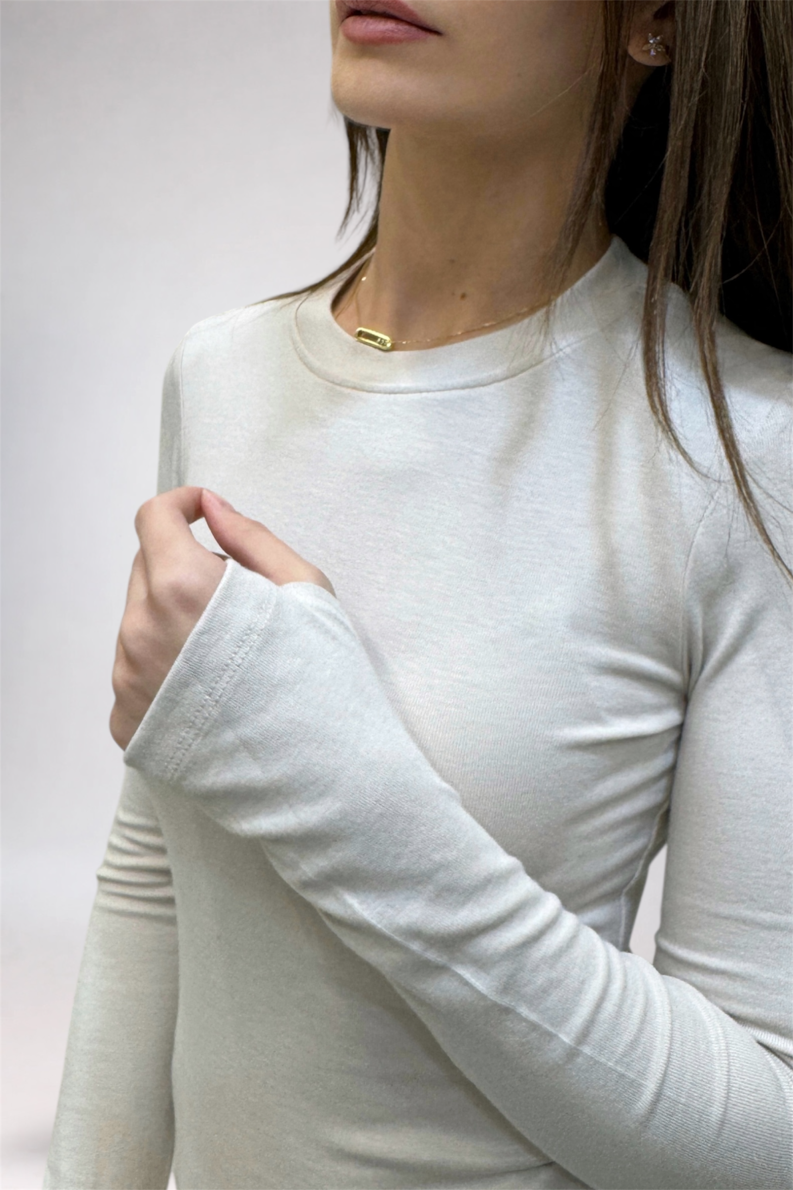Person wearing a white long-sleeve shirt against a plain background