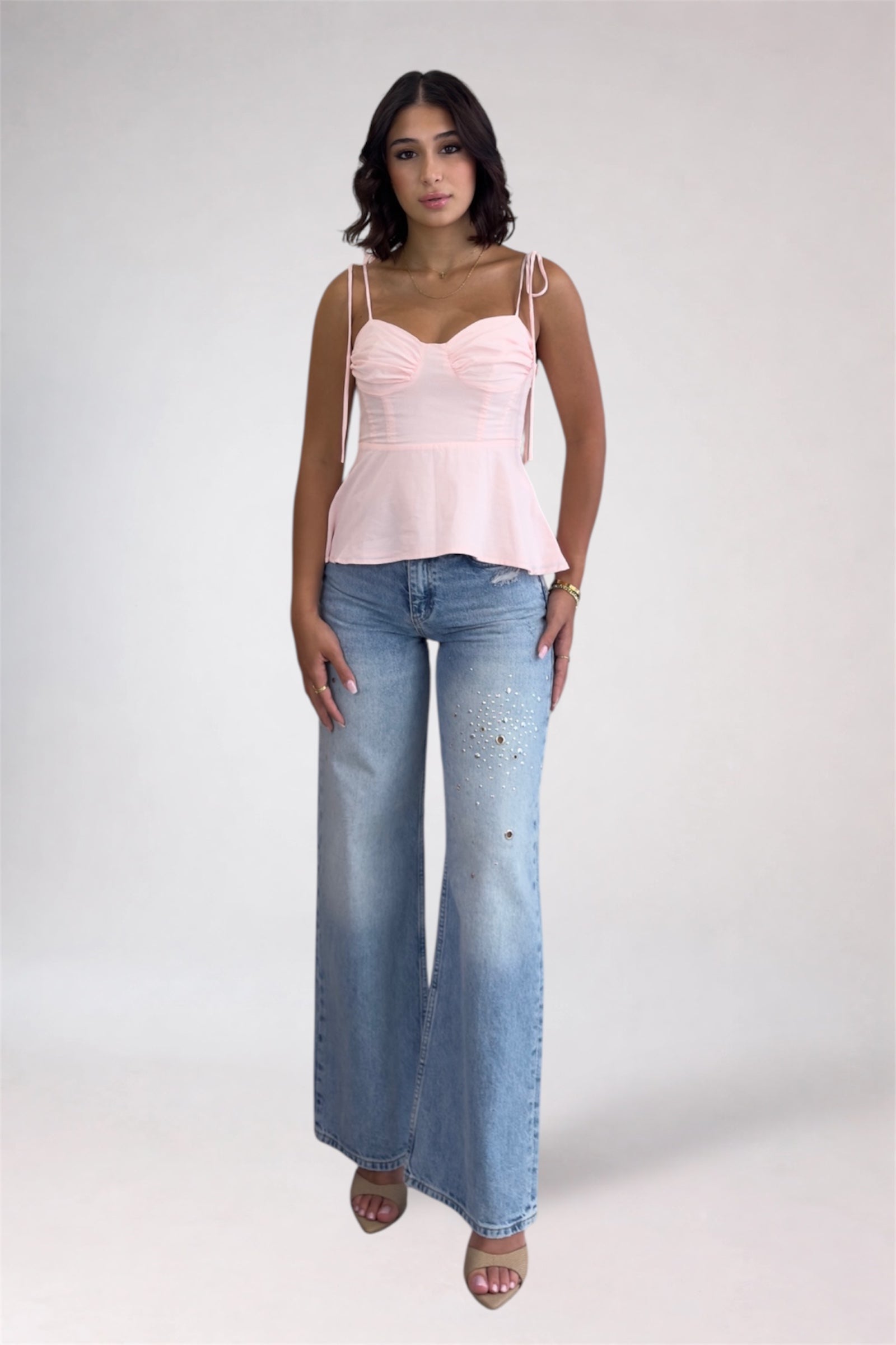 Woman wearing a pink top and blue jeans on a white background