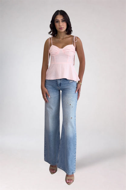 Woman wearing a pink top and blue jeans on a white background