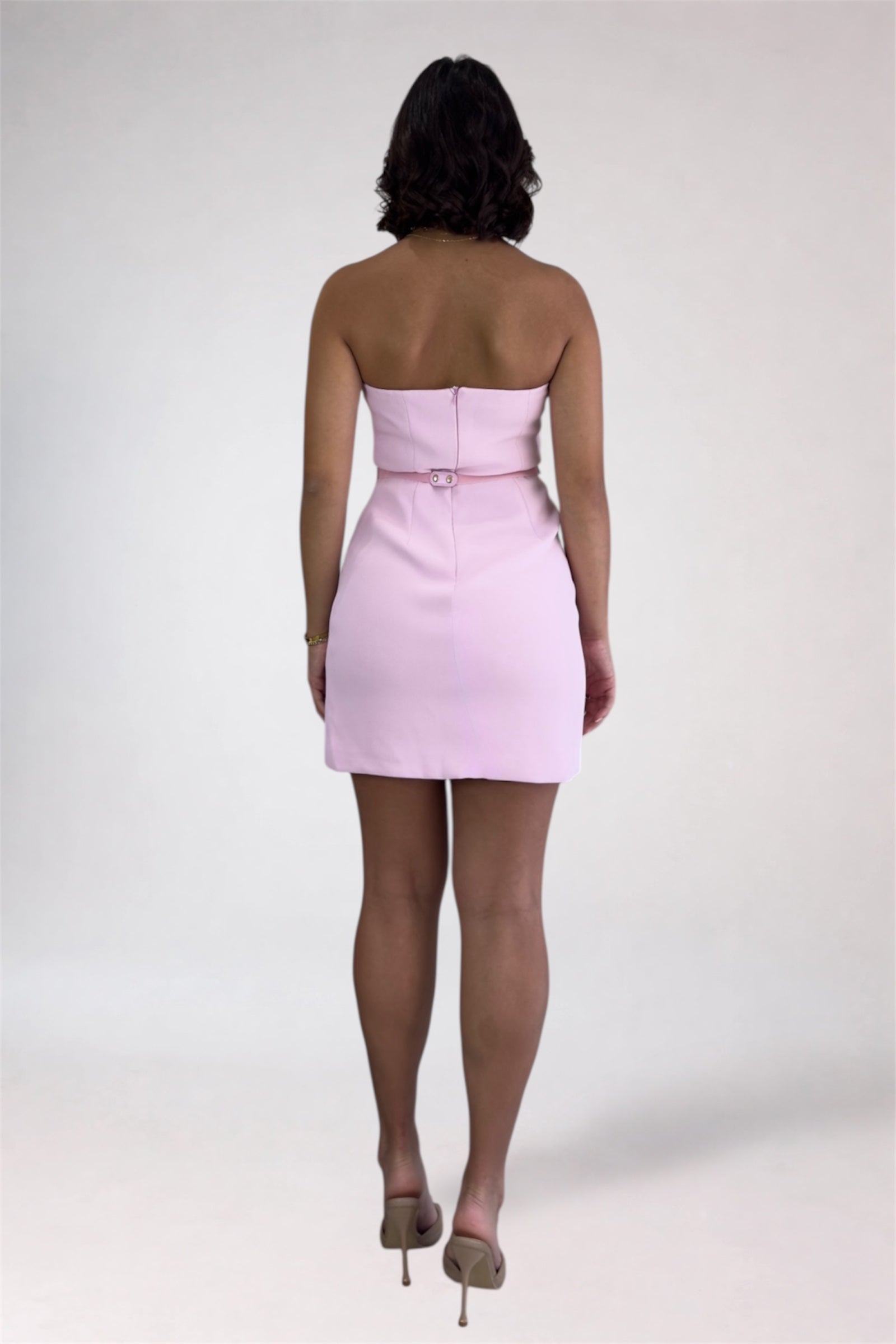 Person wearing a light pink strapless dress on a white background