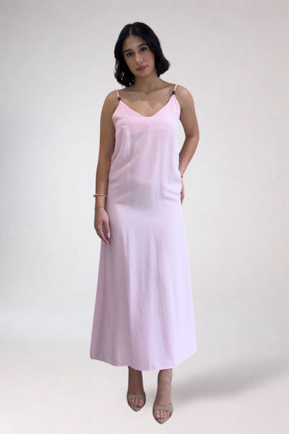 Woman wearing a light pink slip dress on a white background