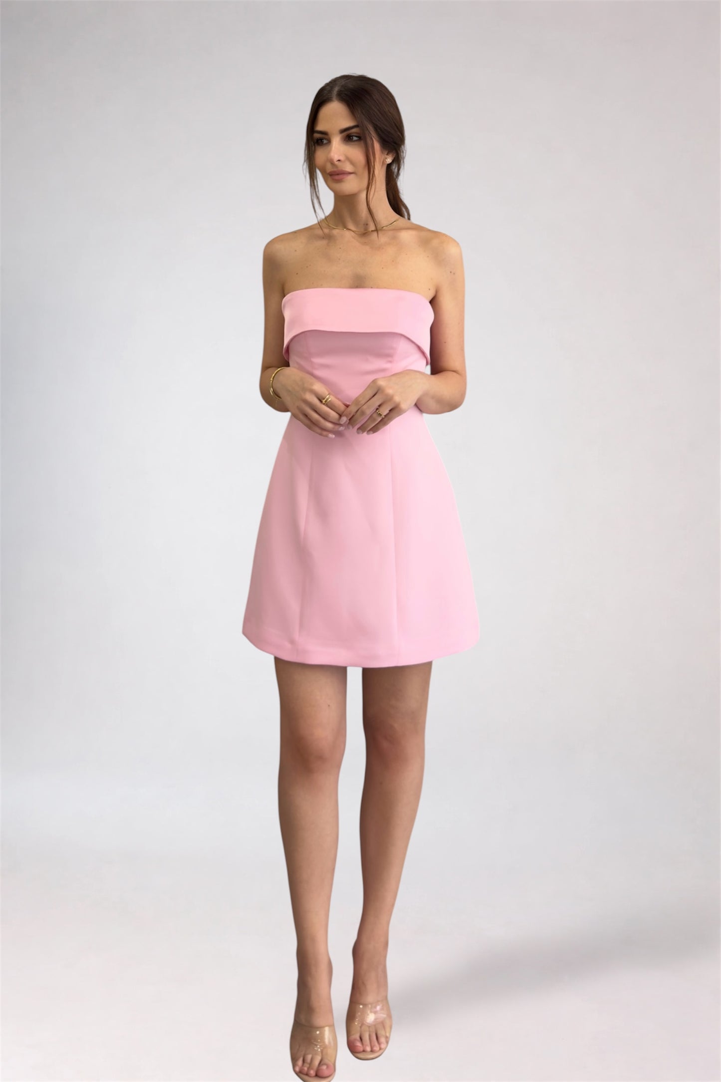 Woman wearing a pink strapless dress on a white background
