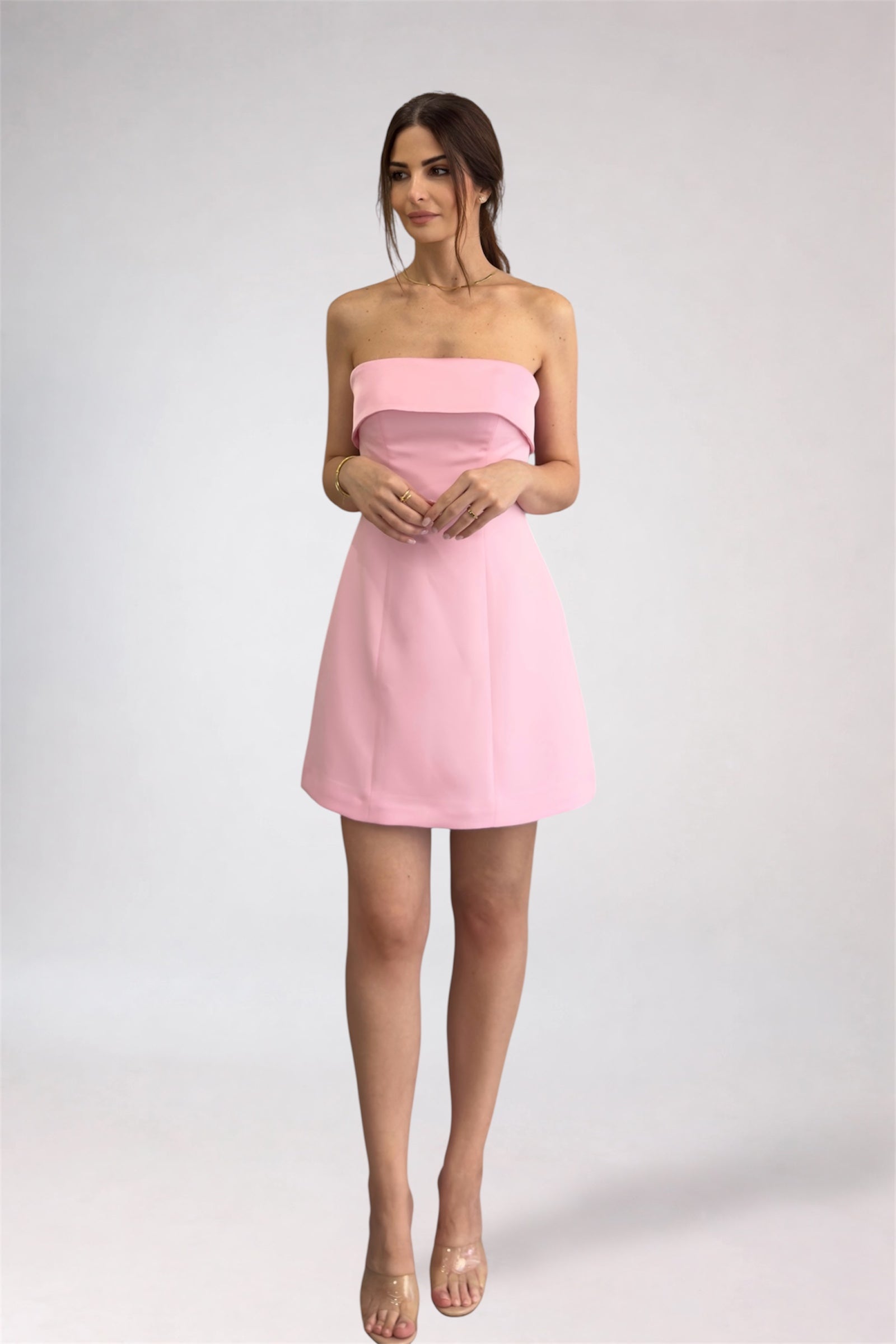 Woman wearing a pink strapless dress on a white background