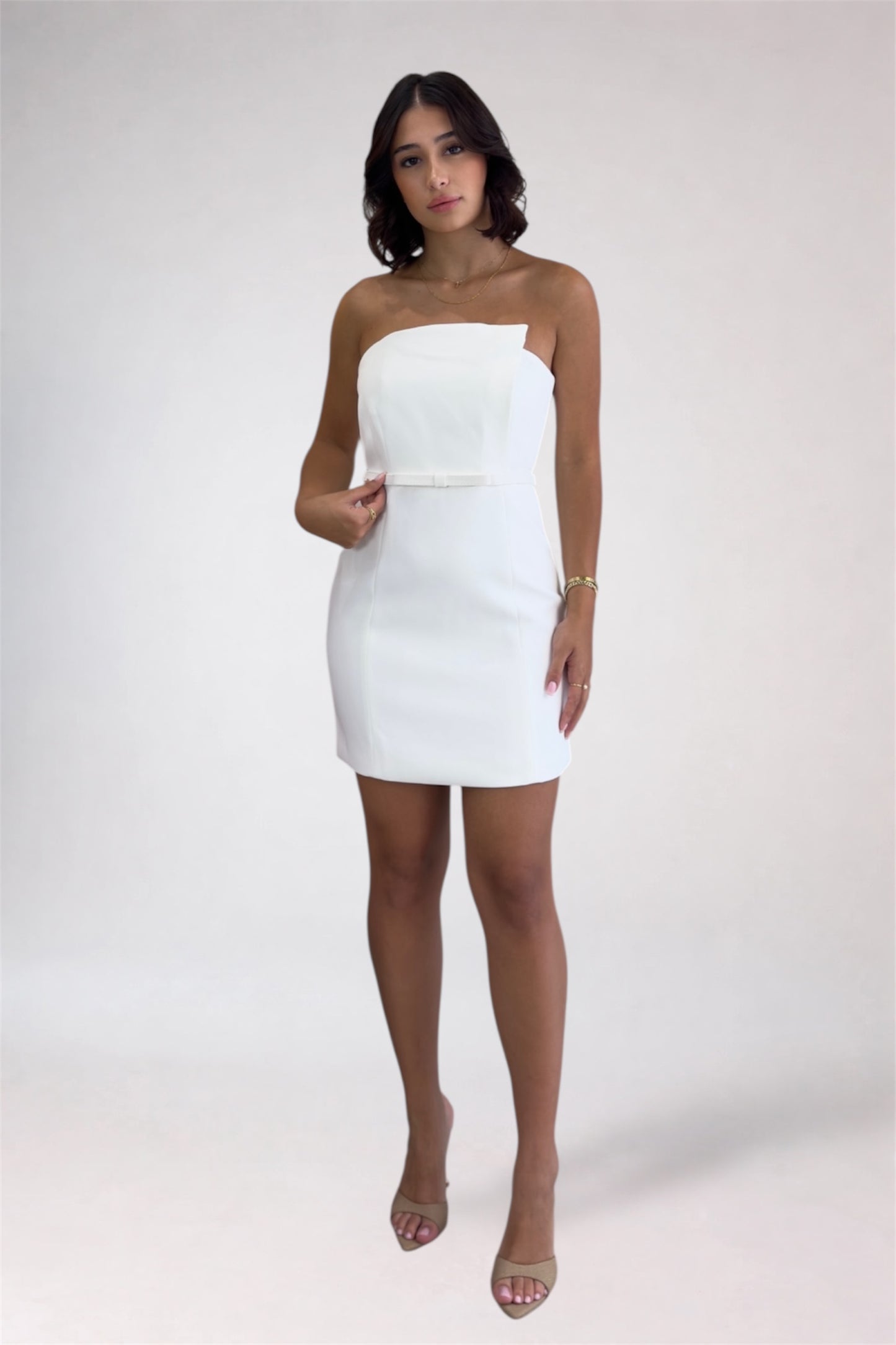 Woman wearing a white strapless dress on a plain background
