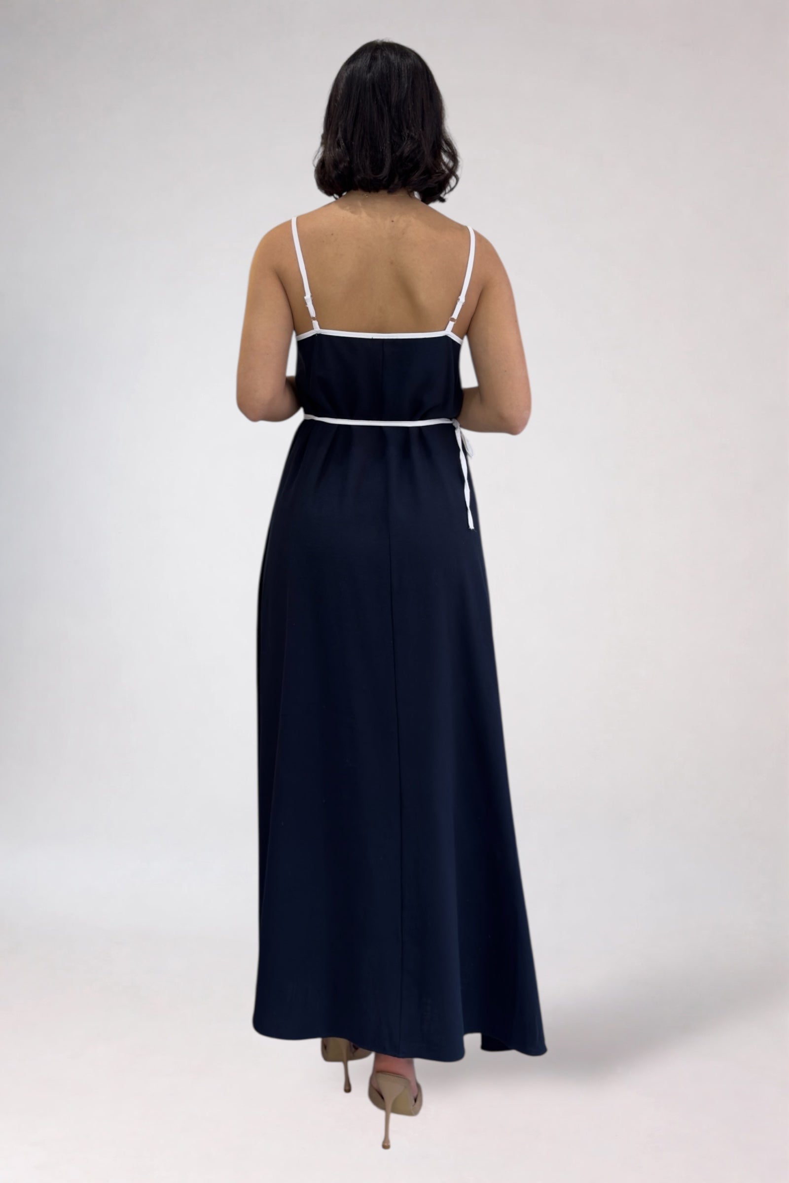 Woman wearing a navy blue dress with white trim on a white background
