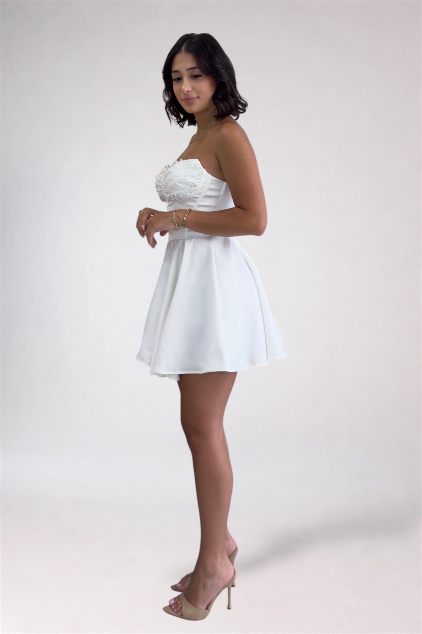 Woman wearing a white strapless dress on a plain background