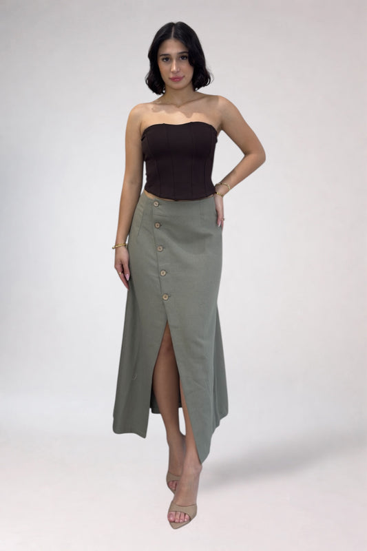 Woman wearing a strapless top and long green skirt on a white background
