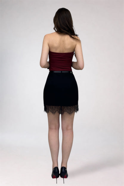 Woman wearing a strapless top and black skirt with lace hem on a white background