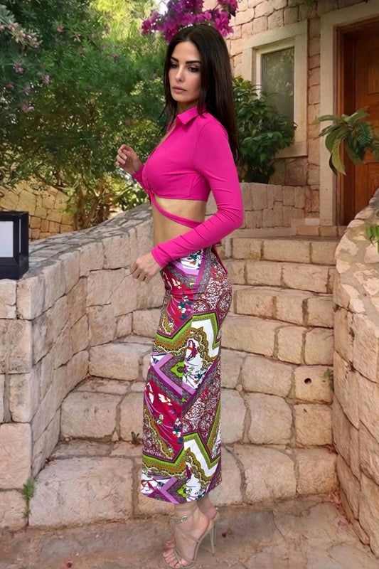 Woman in a bright pink top and colorful patterned pants standing on stone steps outdoors.