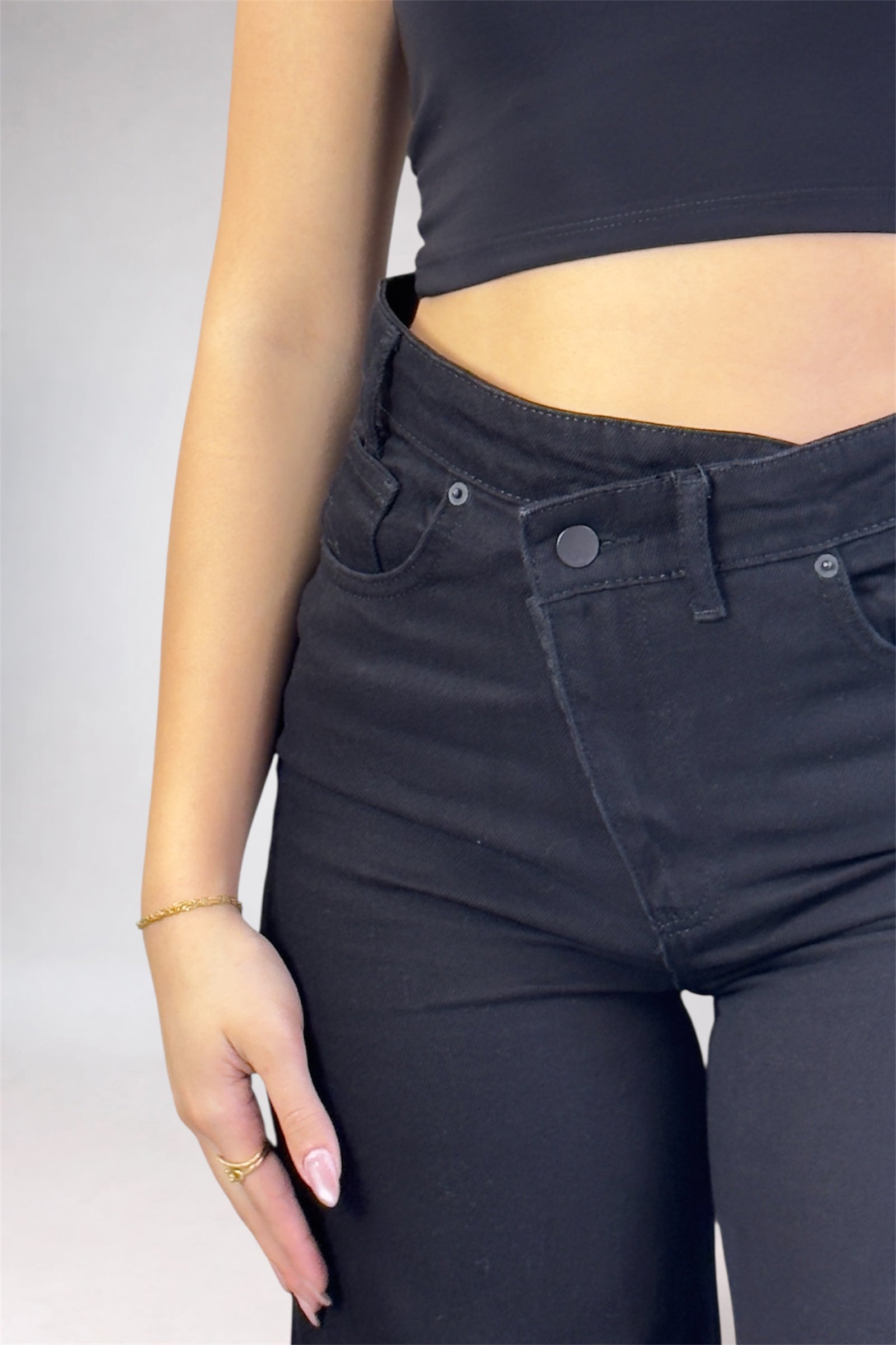 Person wearing black jeans and a black crop top on a plain background