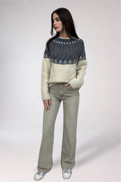 Woman wearing a patterned sweater and jeans on a white background