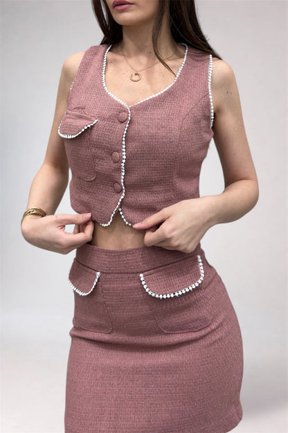 Woman wearing a pink textured outfit with pearl details on a white background