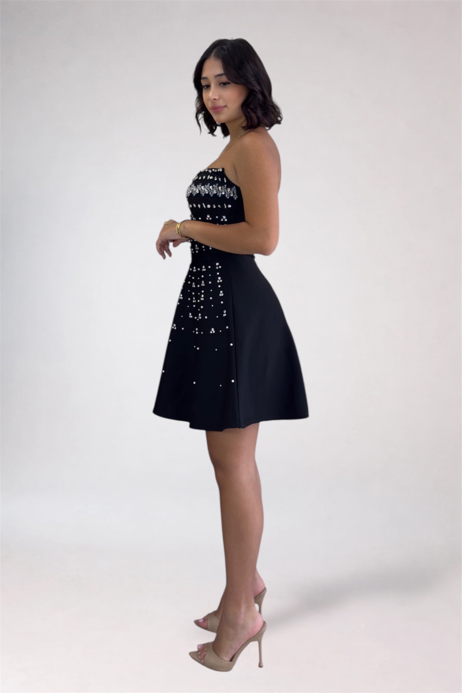 Woman wearing a black dress with white embellishments on a white background