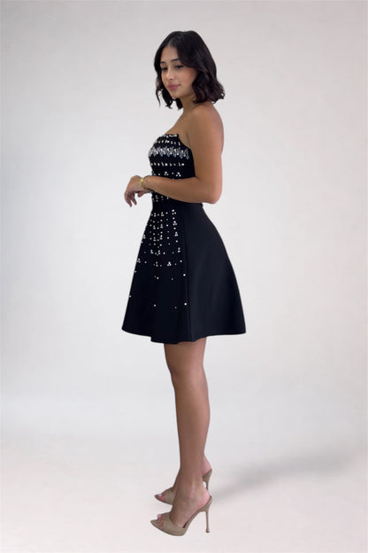 Woman wearing a black dress with white embellishments on a white background