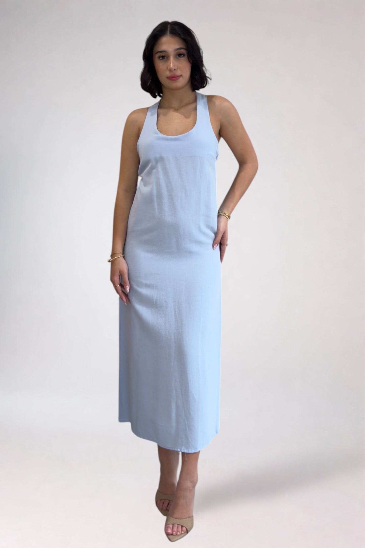 Woman wearing a light blue sleeveless dress against a white background