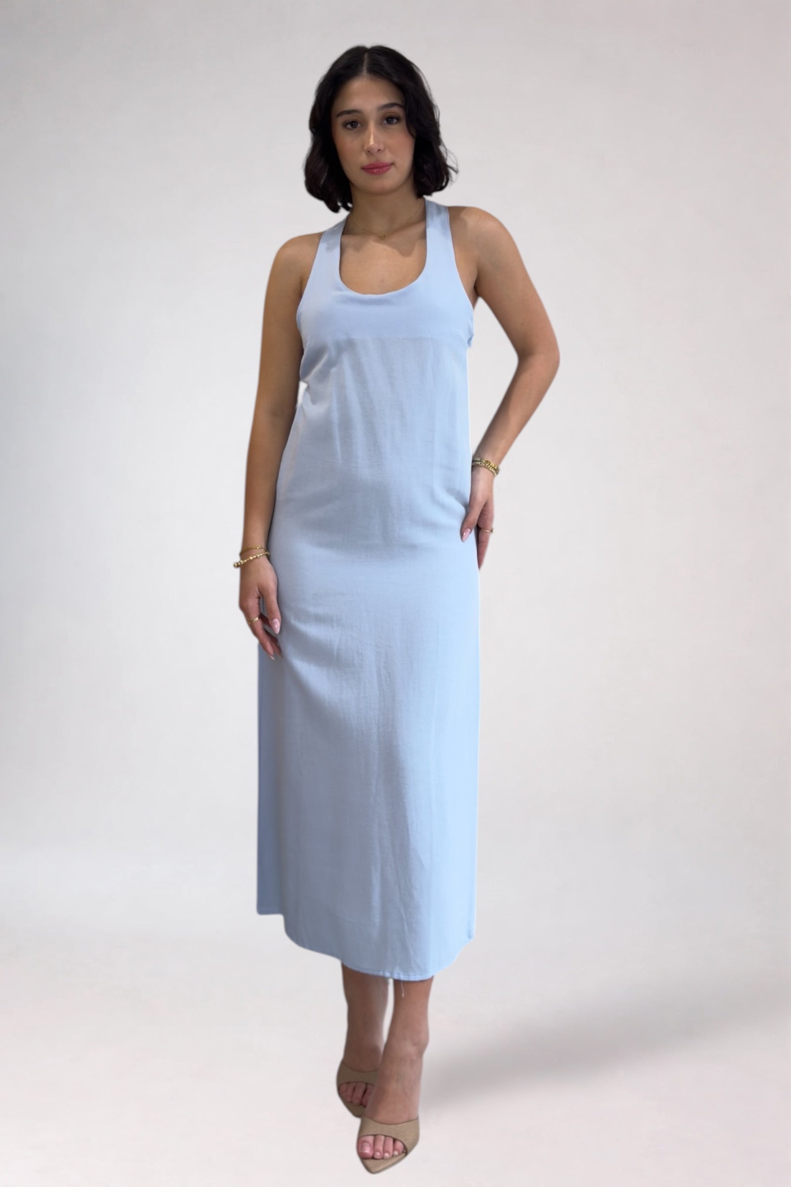 Woman wearing a light blue sleeveless dress against a white background