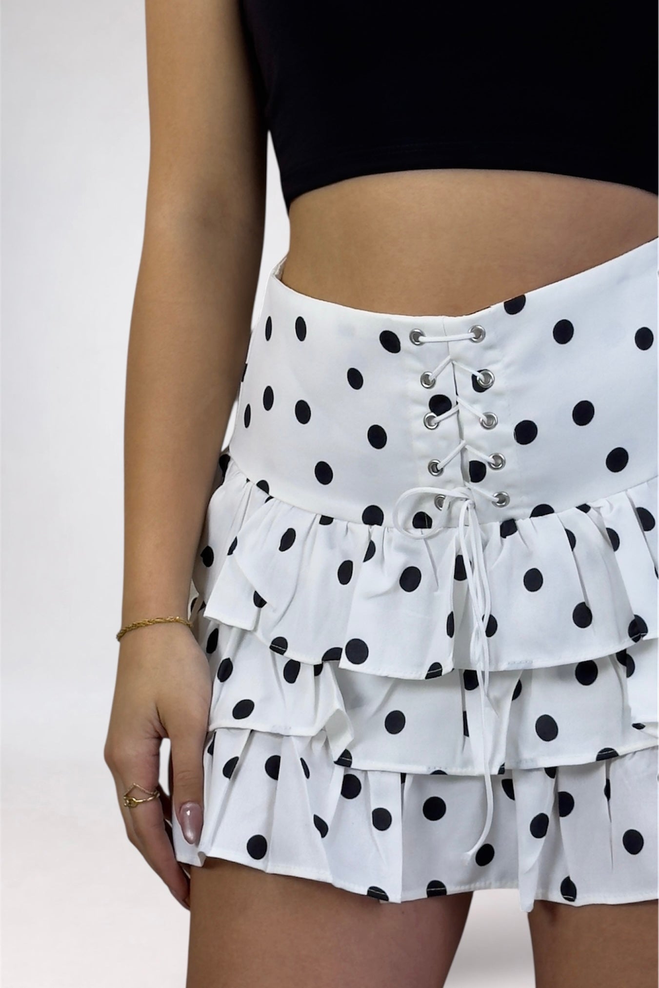 White skirt with black polka dots featuring lace-up front and ruffled layers on a plain background.