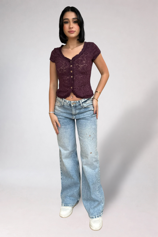 Woman wearing a purple top and blue jeans on a plain background