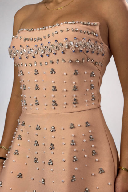 Beige strapless dress with intricate beadwork on a plain background