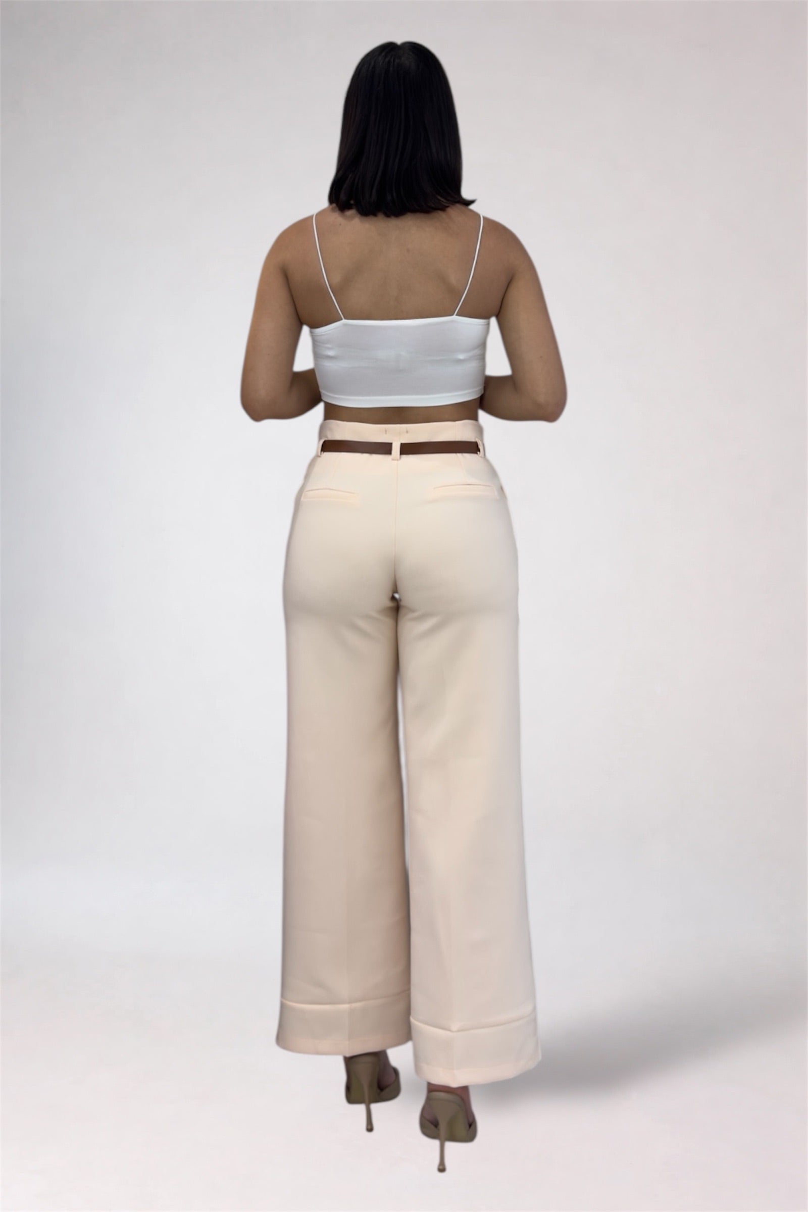 Person wearing a white crop top and beige wide-leg pants on a plain background