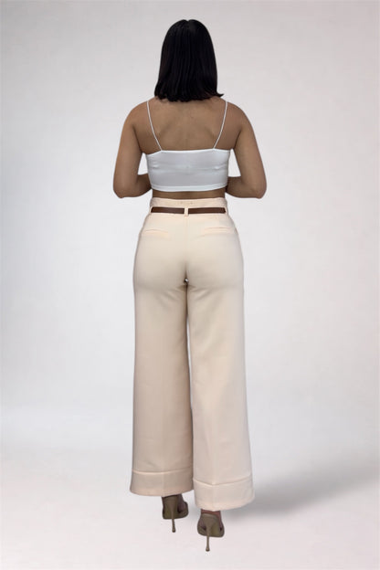 Person wearing a white crop top and beige wide-leg pants on a plain background
