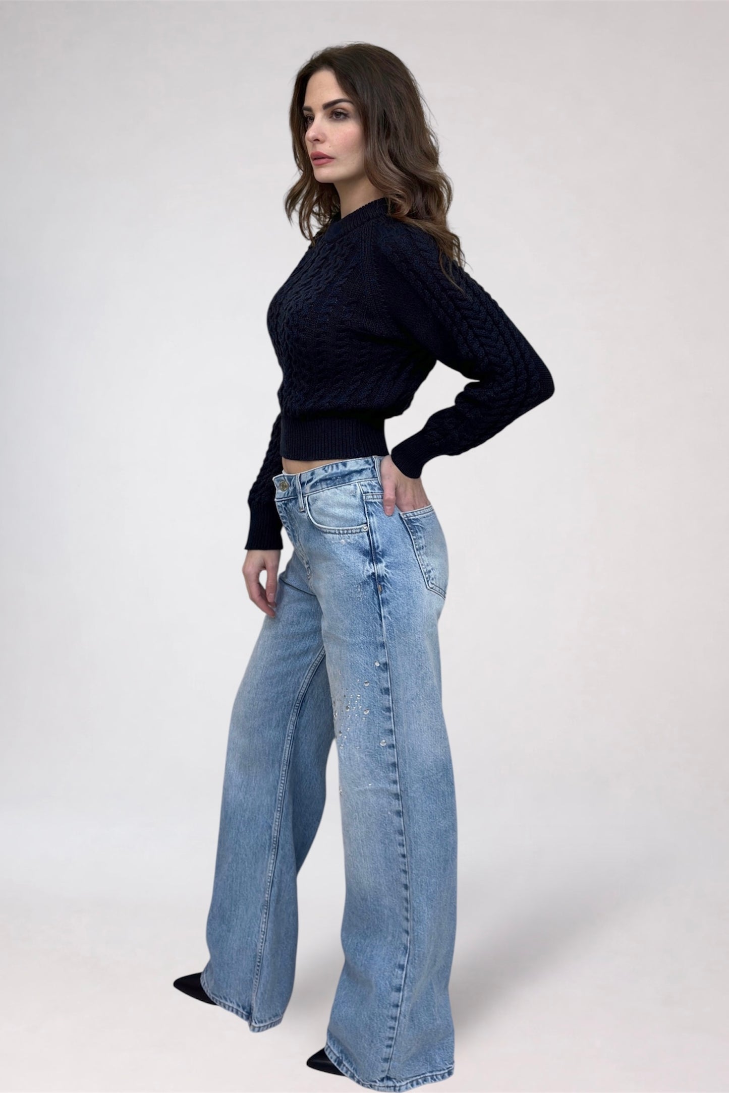 Woman wearing a black sweater and blue jeans on a white background