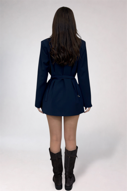 Person wearing a navy blue trench coat and black boots on a white background