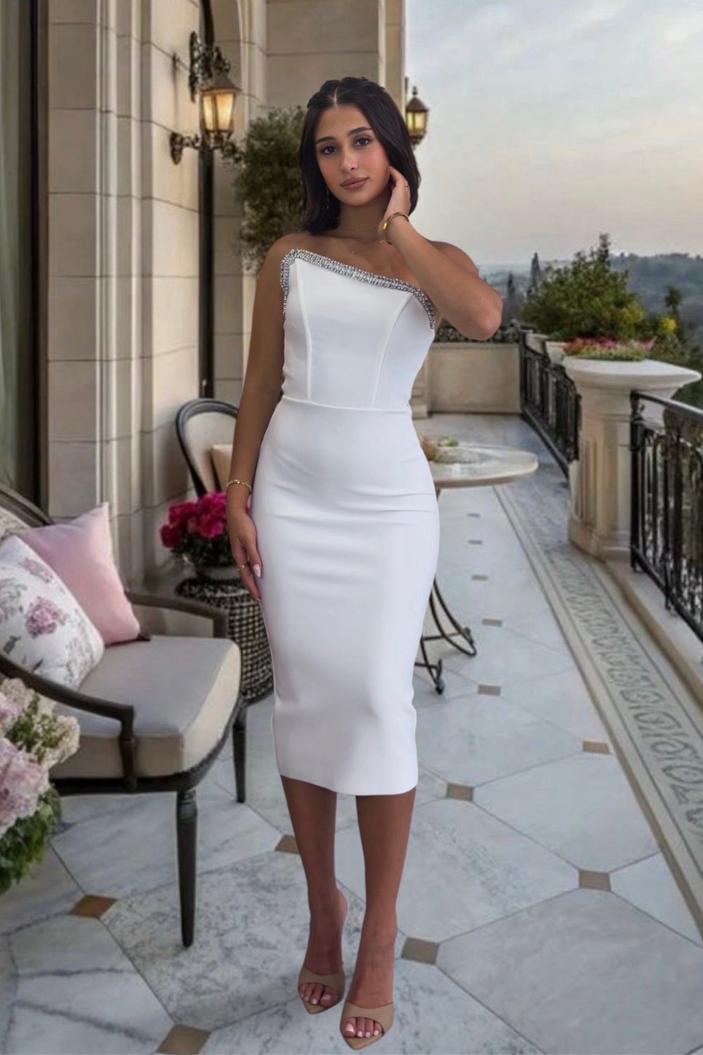 Woman in a white dress standing on a balcony with scenic views