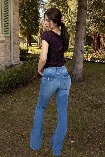 Woman wearing blue jeans and a dark top standing outdoors near a house.