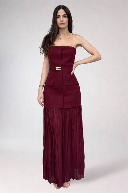 Woman wearing a burgundy strapless dress with a belt on a white background