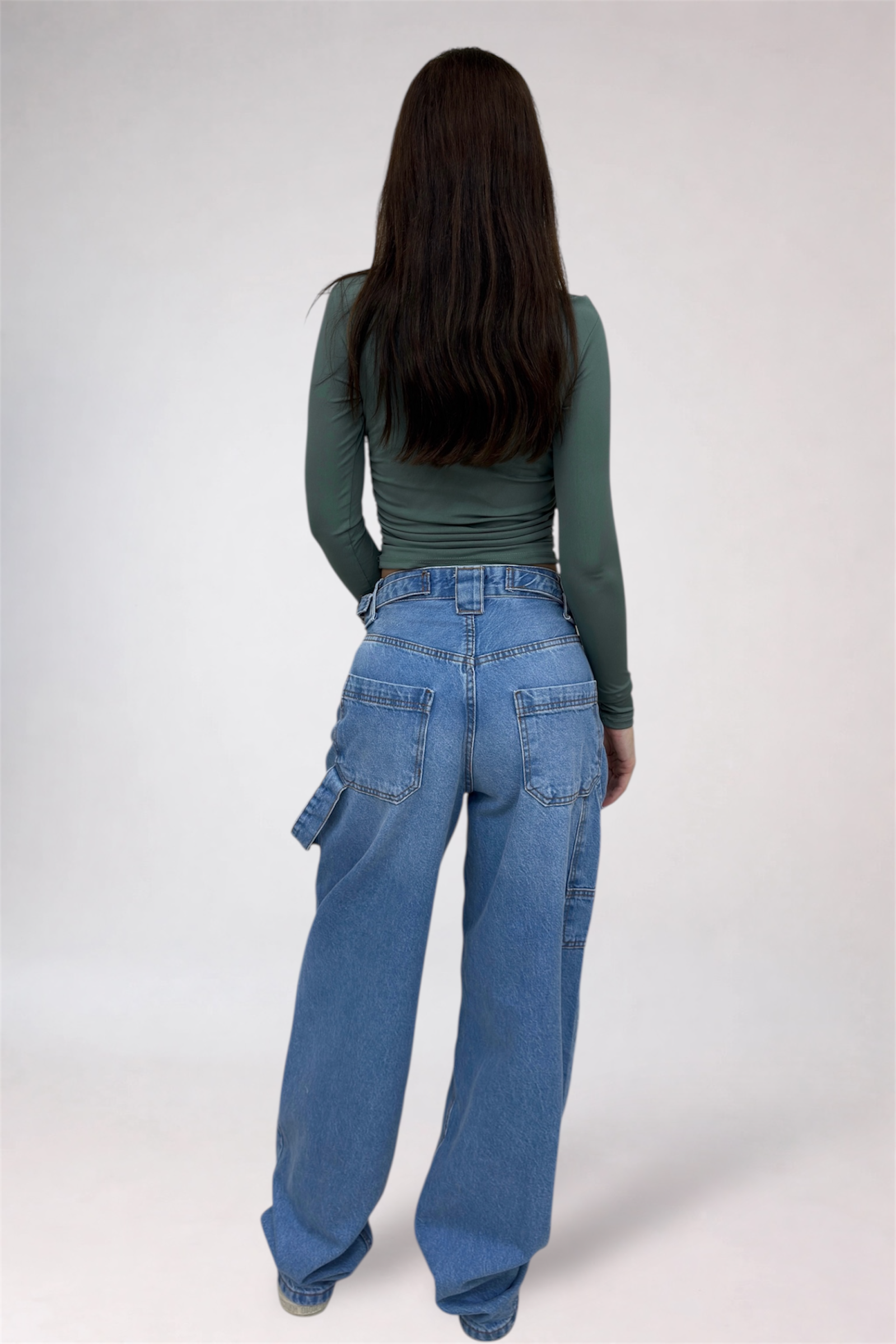 Person wearing blue jeans and a green top on a white background