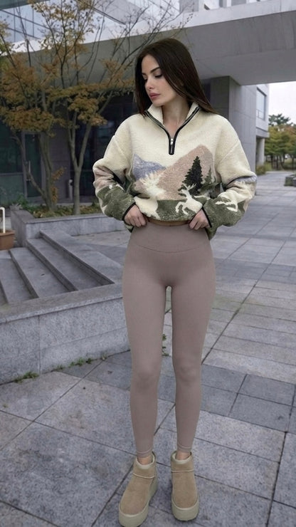 Woman wearing a patterned sweater and beige leggings standing on a sidewalk.