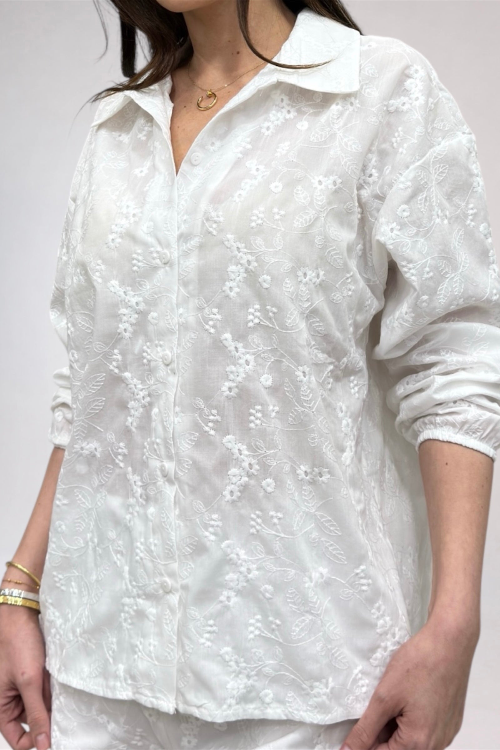 White floral embroidered shirt worn by a person on a plain background