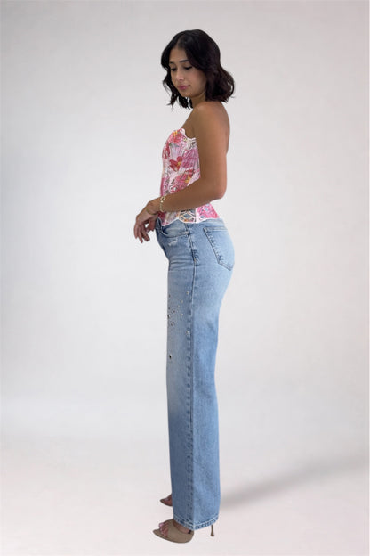 Woman wearing a floral top and light blue jeans on a white background