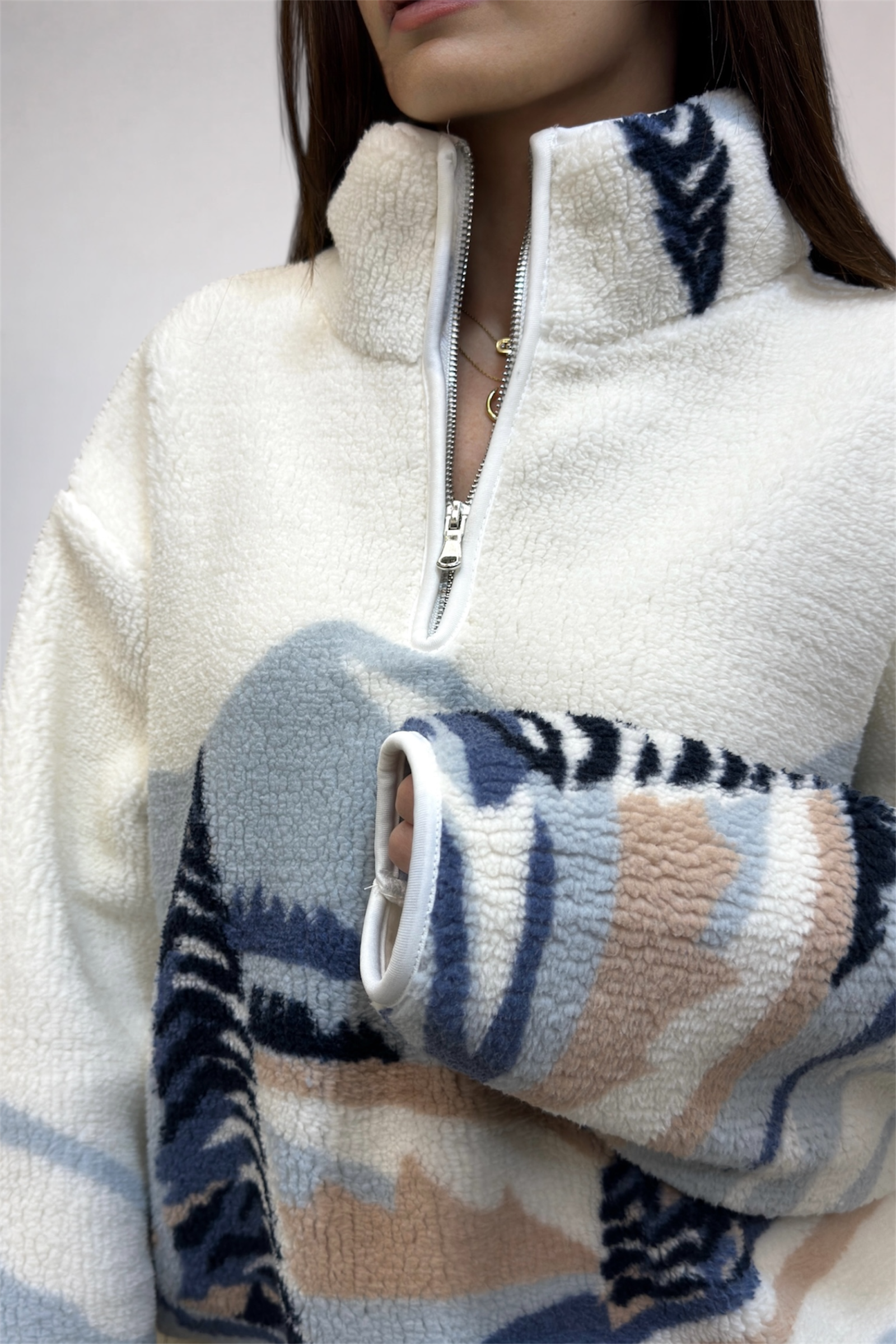 Close-up of a person wearing a white fleece jacket with patterned sleeves.