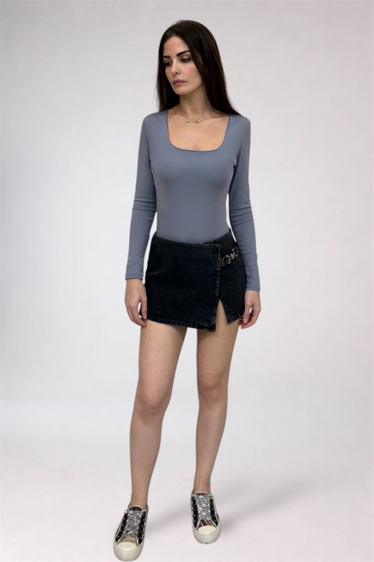 Woman wearing a gray long-sleeve top and black denim skirt on a white background