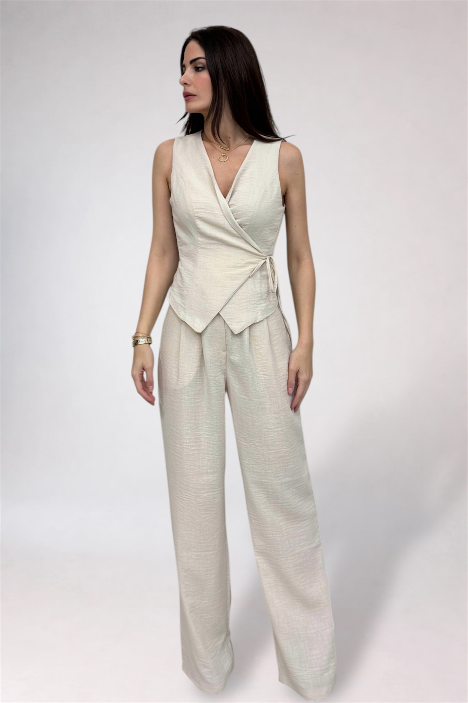 Woman wearing a light-colored sleeveless top and wide-leg pants on a white background