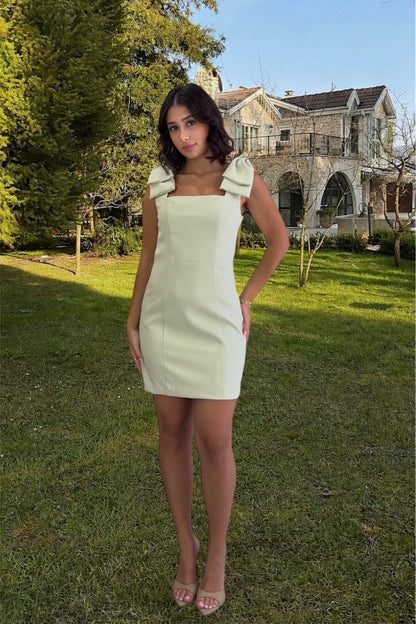 Woman in a white dress standing in a grassy area with a house in the background