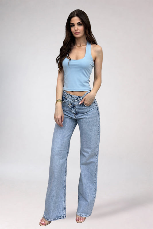 Woman wearing a light blue tank top and jeans on a white background