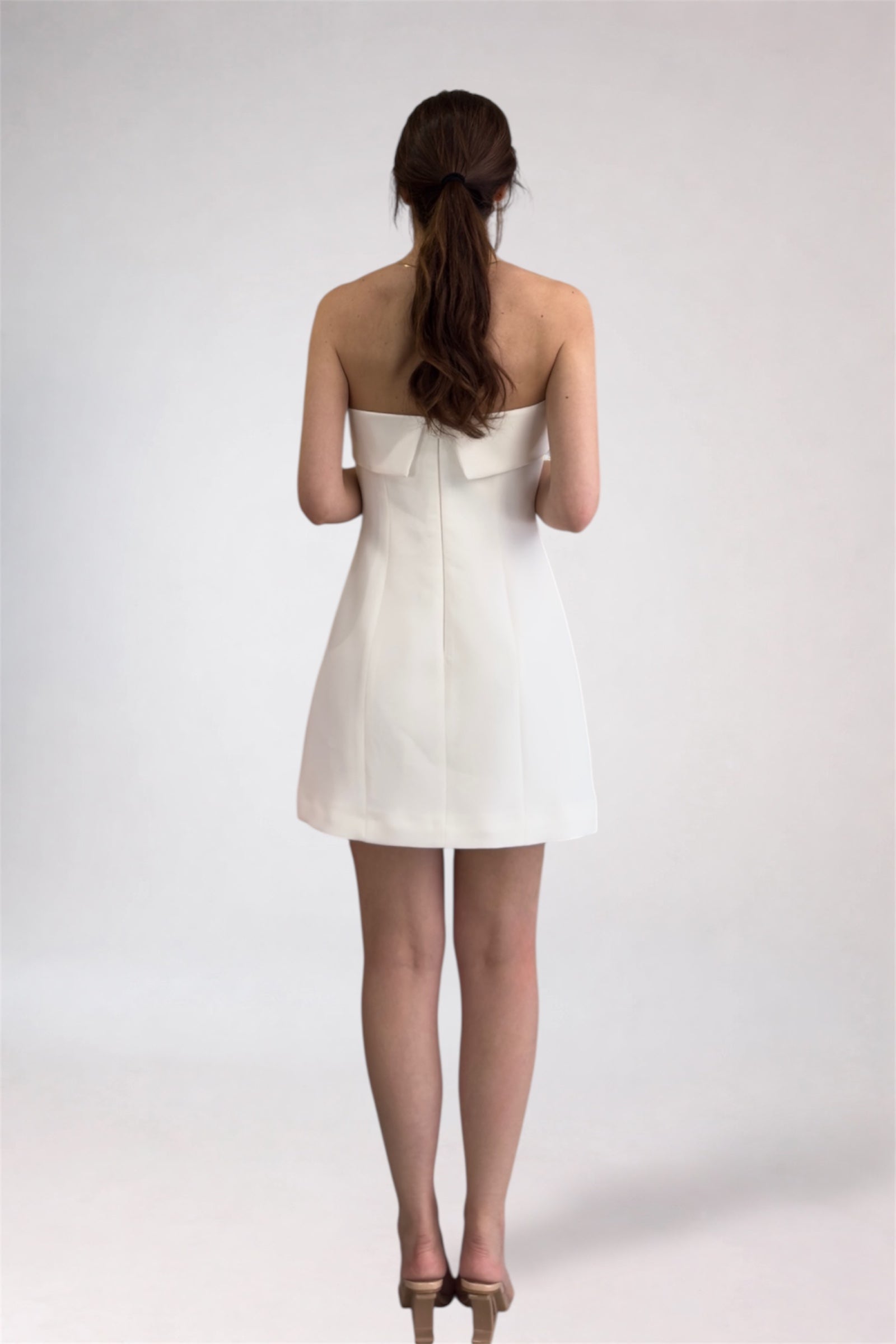 Woman wearing a white strapless dress on a plain background