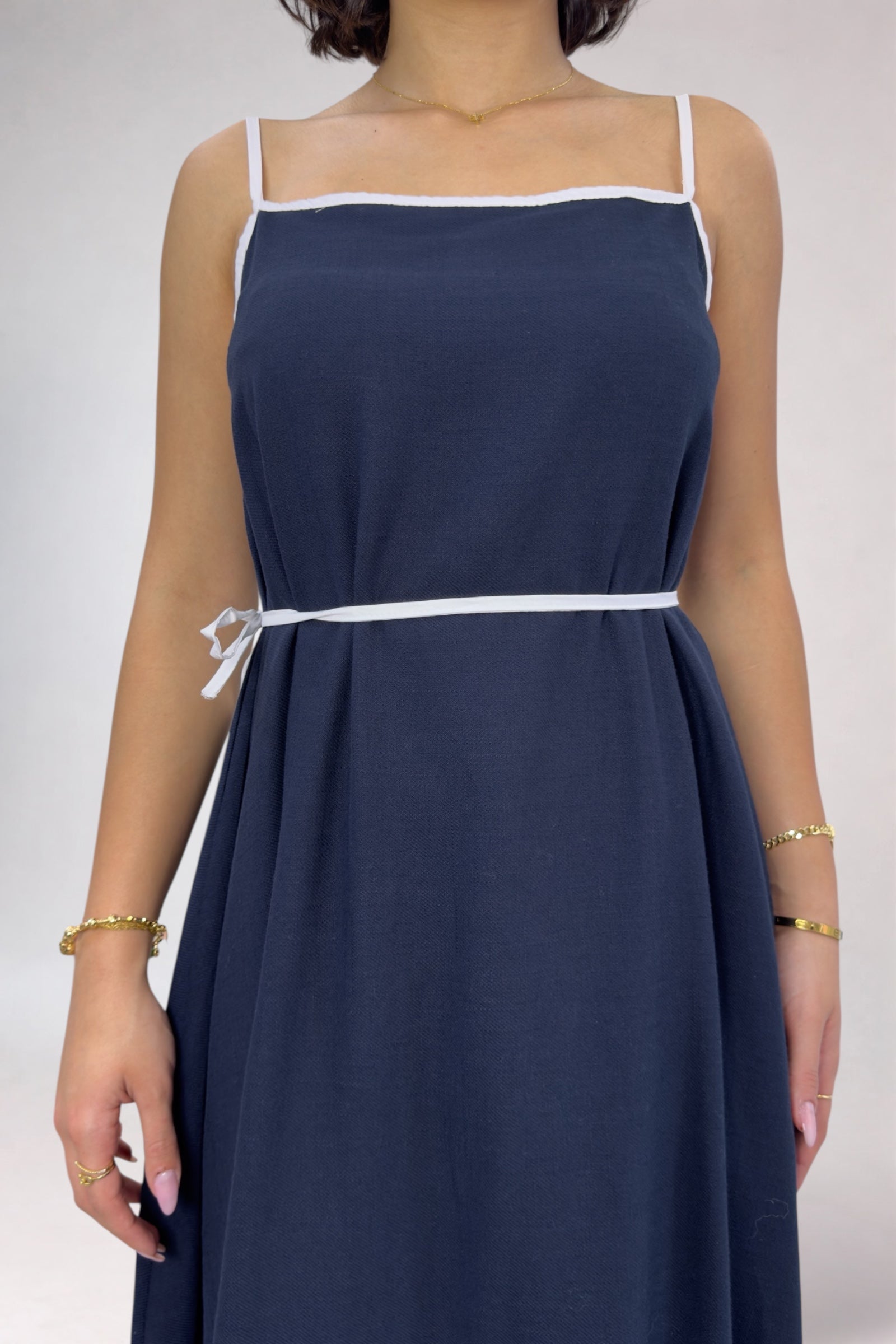 Navy blue dress with white trim on a plain background