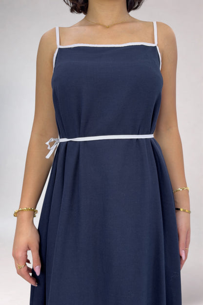Navy blue dress with white trim on a plain background